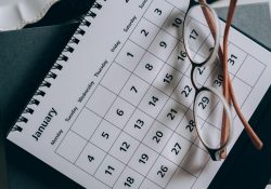 A close-up of a January calendar with eyeglasses on a table, emphasizing planning and organization.